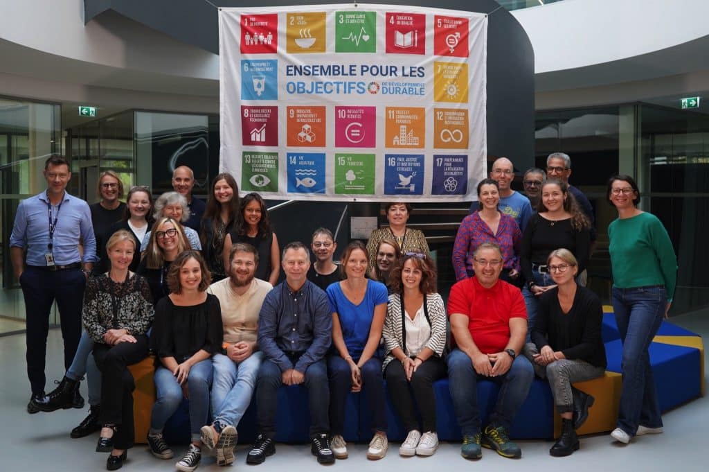 Photo d'équipe de GENFIT posant devant le drapeau des nations unies sur les 17 objectifs de développement durable